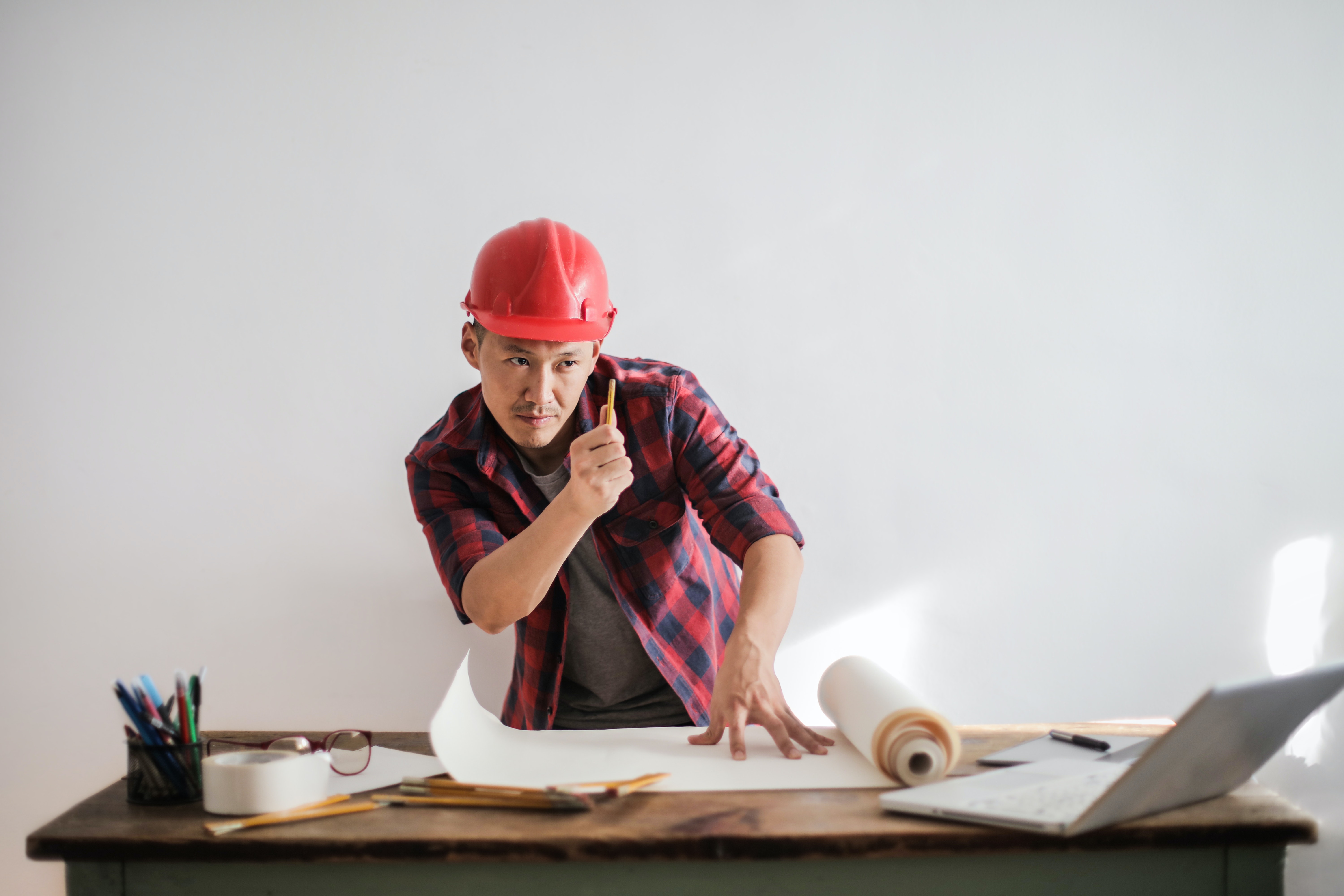 architect wearing a red hard hat poring over his designs